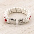 A white and red paracord bracelet with its silver metal buckle unlatched on a light stone surface.