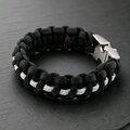 A close-up view of the black and white braided paracord bracelet on a dark slate background, angled to show the texture of the weave.