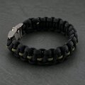 A close-up view of the paracord bracelet laid out flat on a dark textured background.