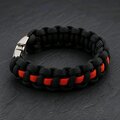 A thick paracord bracelet made of black cord with a thin orange center line, fastened with a silver buckle on a dark background.