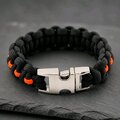 Close-up of the polished silver side-release buckle fastened on the black and orange survival bracelet.
