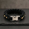 A close-up shot of the black paracord bracelet featuring a thin gold stripe down the middle and a locked silver buckle.