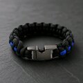 The black tactical paracord bracelet is shown closed with its dark metallic side-release buckle facing forward.