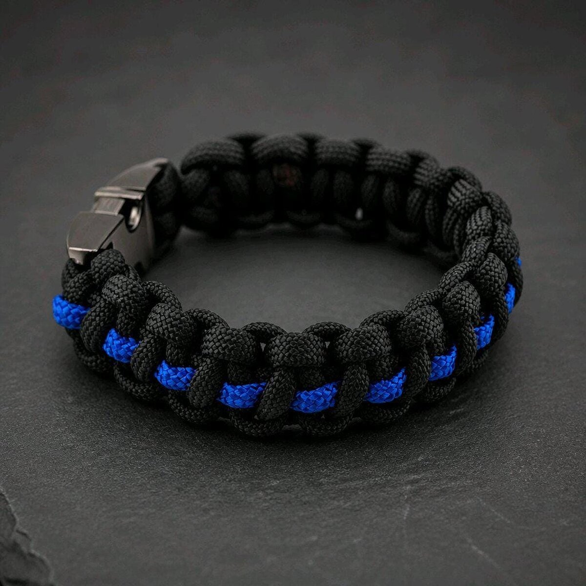 A close-up view of the black and blue woven paracord bracelet featuring a dark gunmetal buckle.
