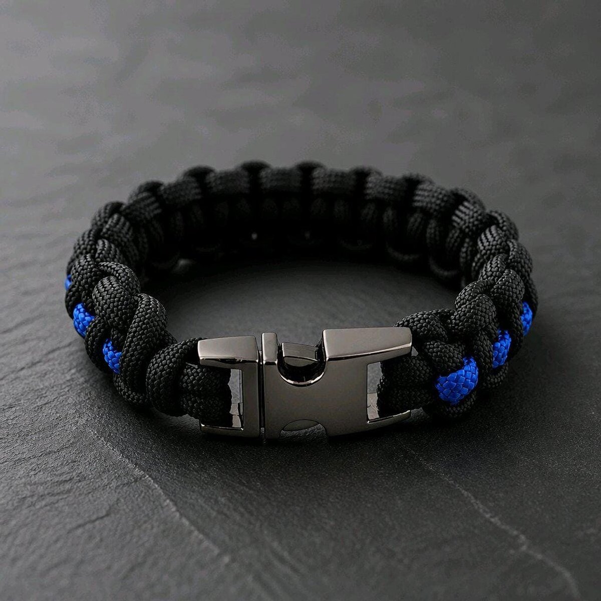 The black tactical paracord bracelet is shown closed with its dark metallic side-release buckle facing forward.