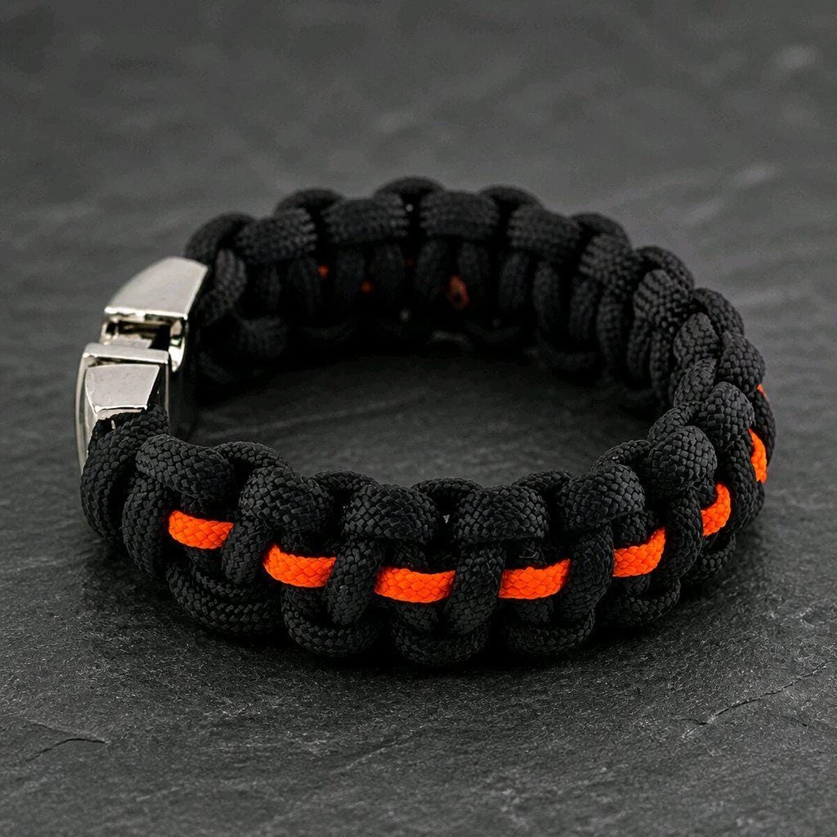 The reverse side of the thick black paracord bracelet with a thin orange stripe running through the center.