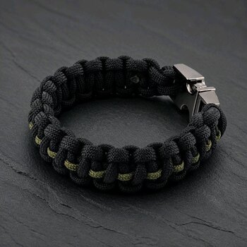 The black paracord bracelet angled on the slate surface, showing the interwoven olive green center stripe.