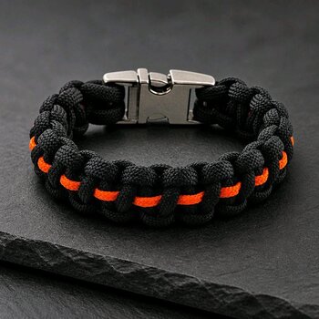 A black and orange paracord bracelet with a silver side-release buckle resting on dark slate.